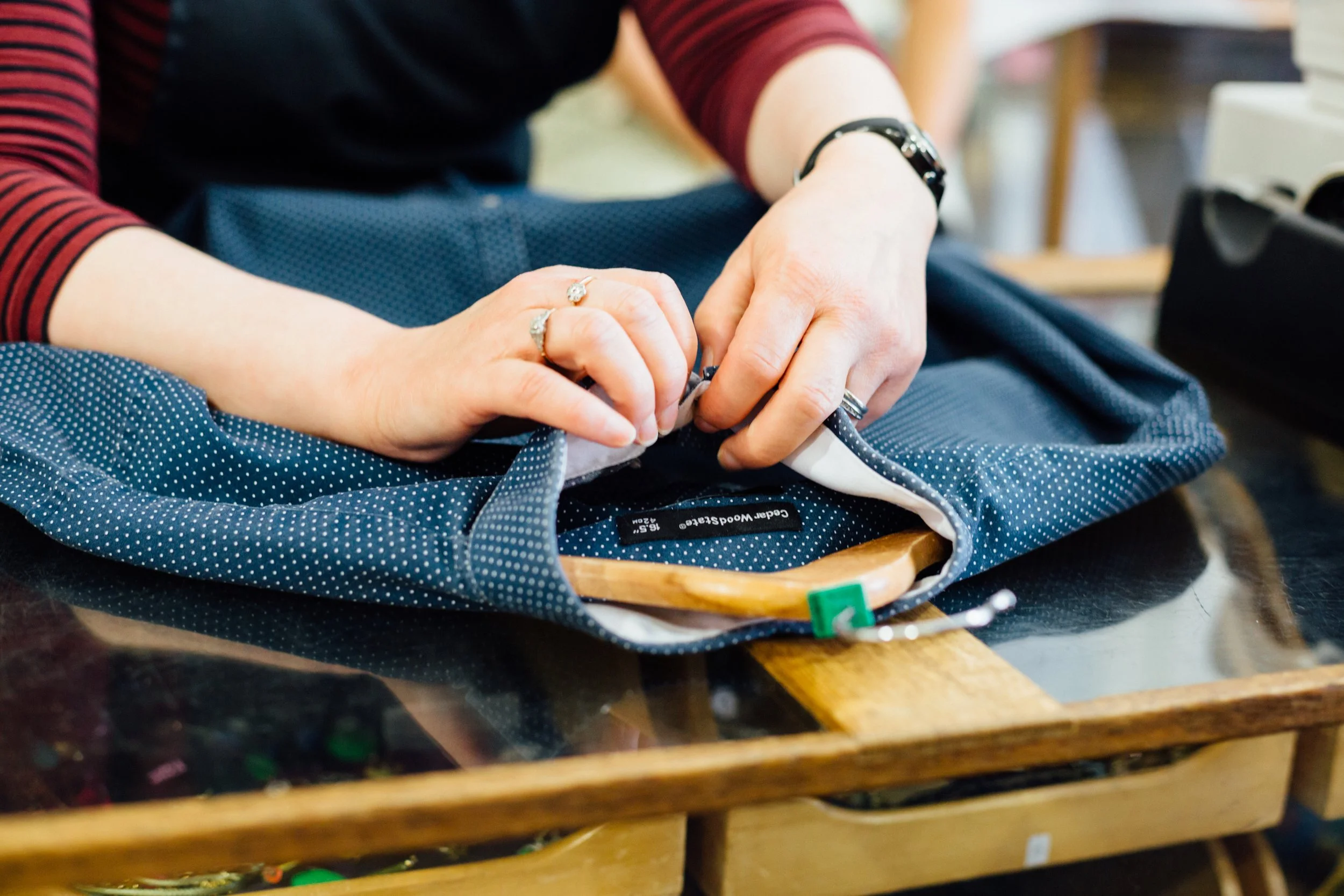 Close-up of a person sewing fabric with a sewing machine on a wooden table.