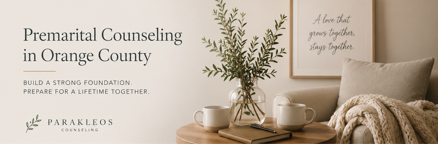 Living room with a beige sofa, a blanket, framed quote on the wall, wooden table with a journal, pen, mugs, and a glass vase with greenery.