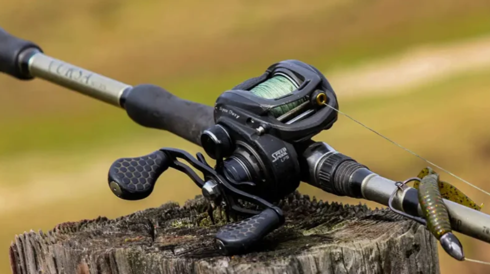 Fishing bait caster with reel and lure resting on a tree stump in an outdoor setting.