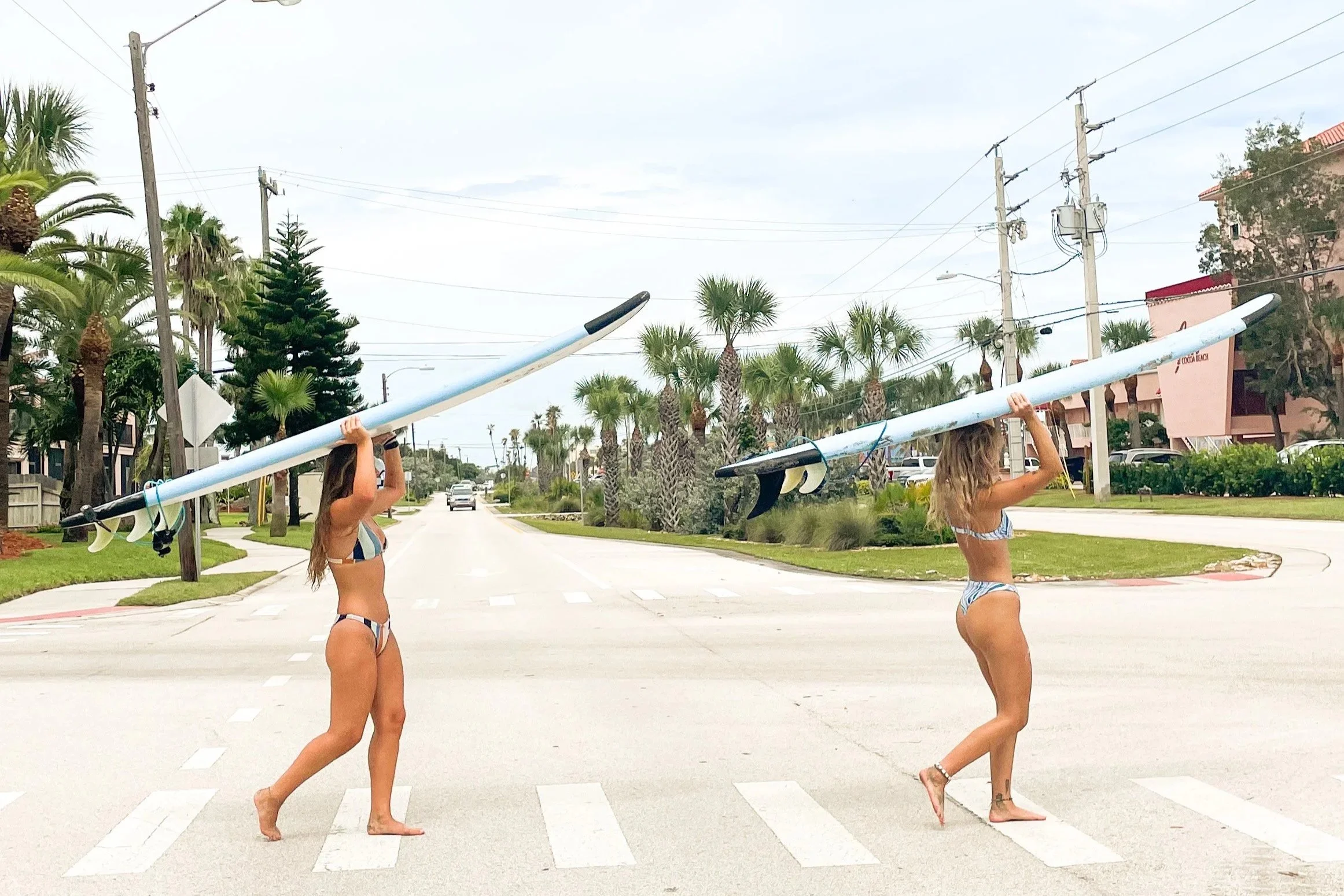 Two women carrying surfboards on a sunny beach day