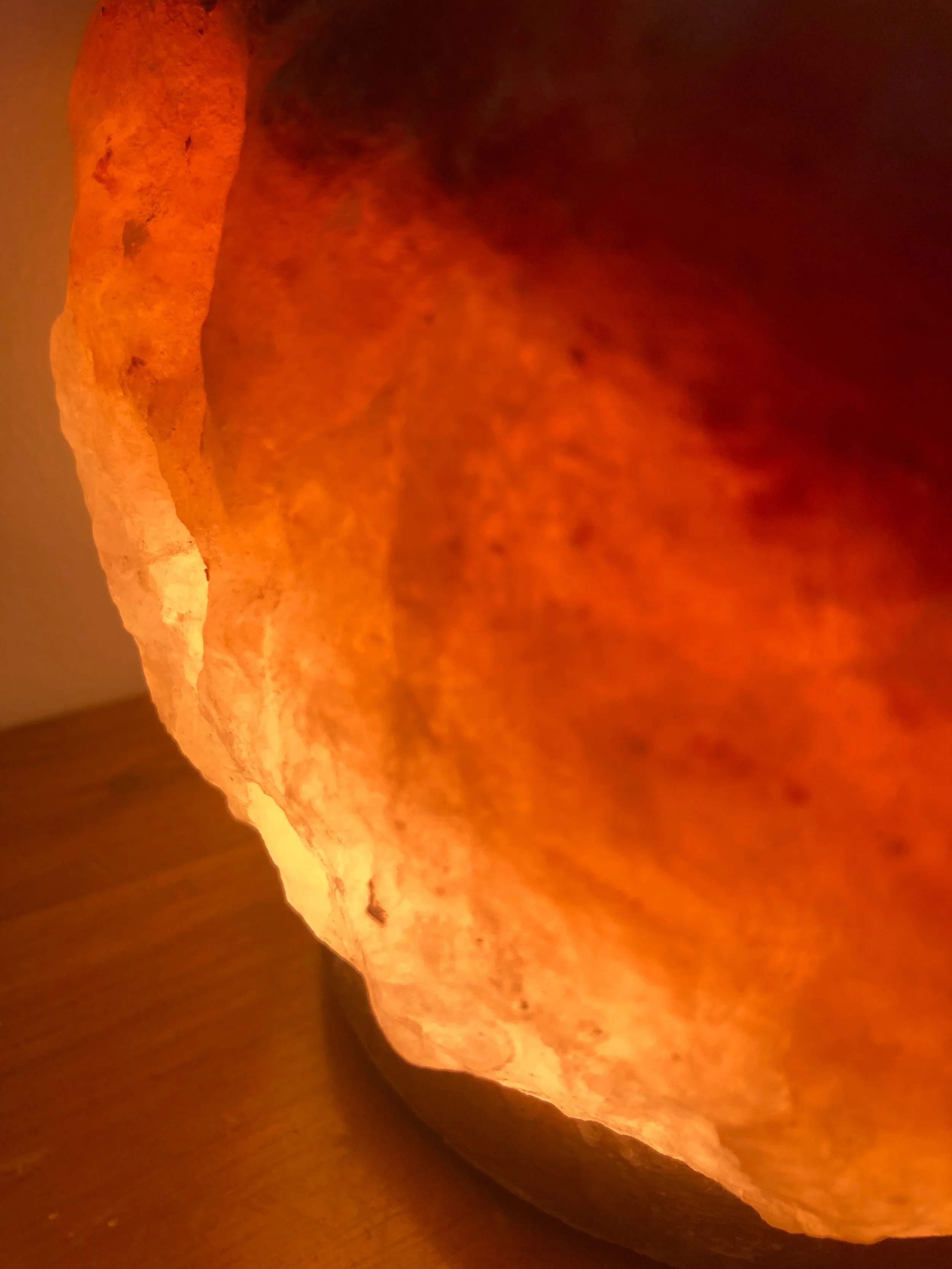 Gros plan d'une lampe de pierre de sel de l'Himalaya illumée, émettant une lumière chaude orange.