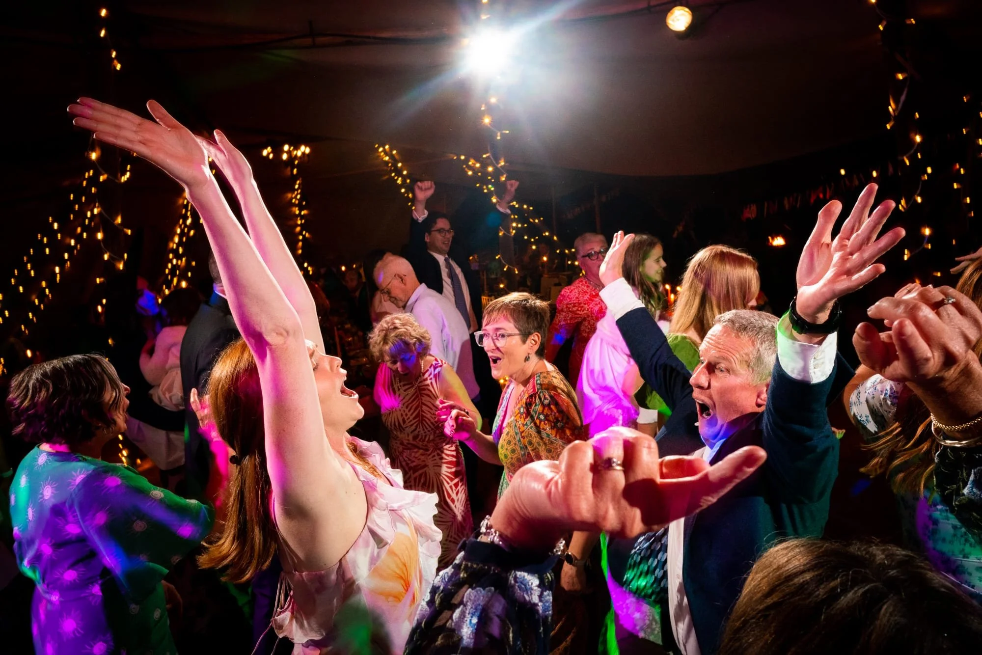 Wedding guests with hands in the air dancing to live music from Revolve Party Band
