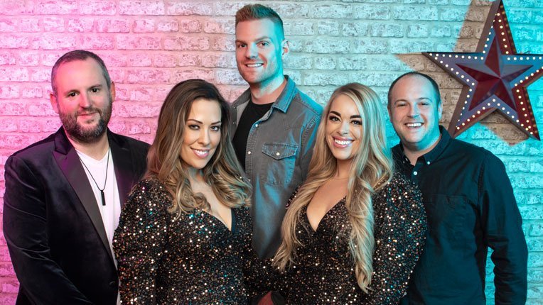 Revolve Party Band members, one of the most popular wedding bands in Essex, posing against a brick wall