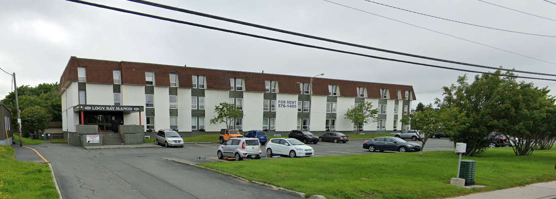 Multi-story white apartment building with brown roof and a