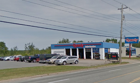 Speedy Auto Service auto repair shop with several cars parked outside, located along a road with utility poles and power lines.
