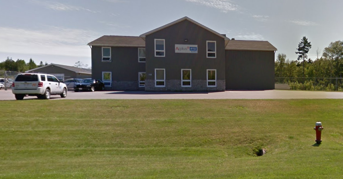 A two-story gray building with a sign reading 'Aplus' and 'HIT' on the front, parked cars nearby, and a grassy field with a fire hydrant in the foreground.