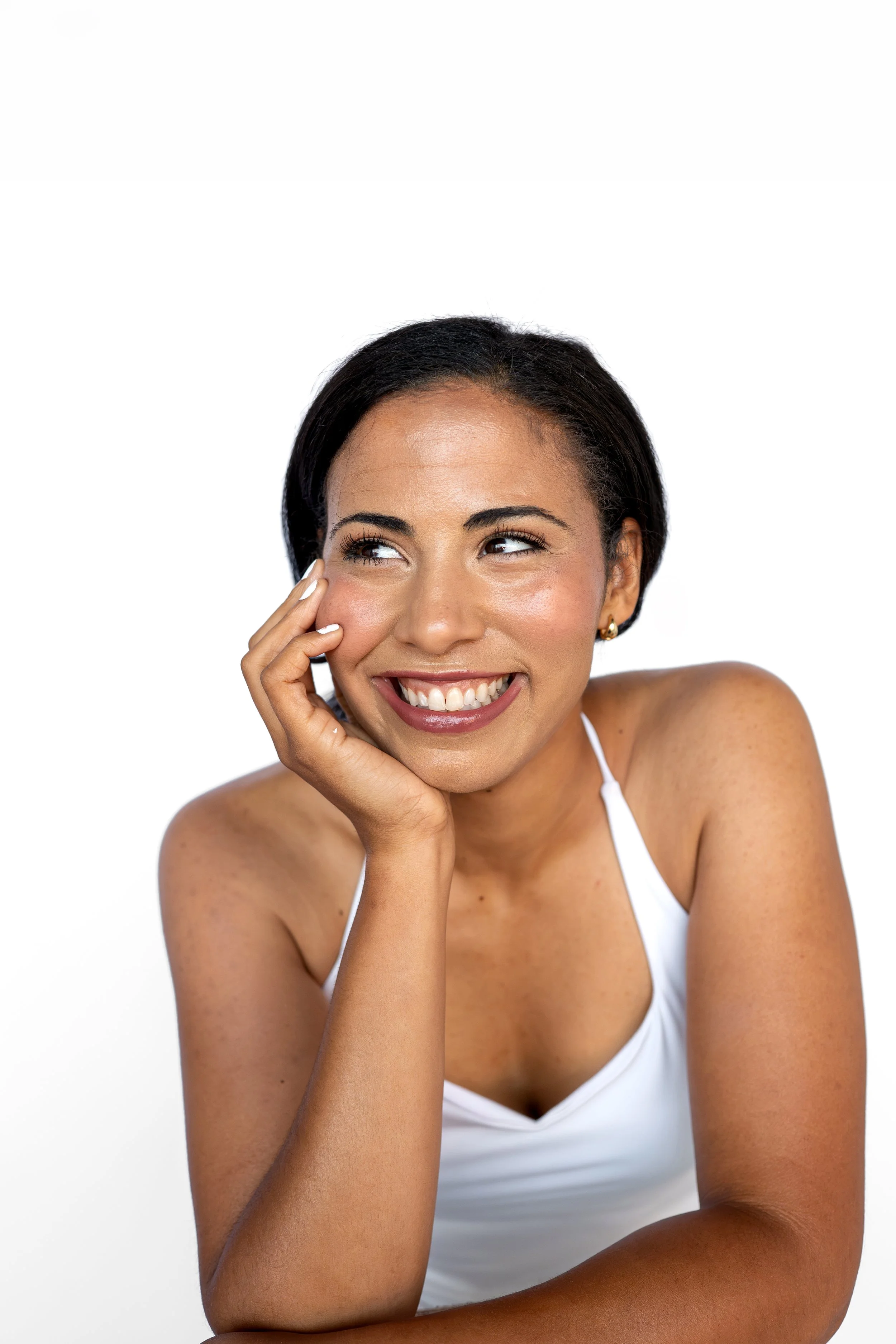 Woman in a white tank top smiles at the best blowout salon in Niles Ohio.