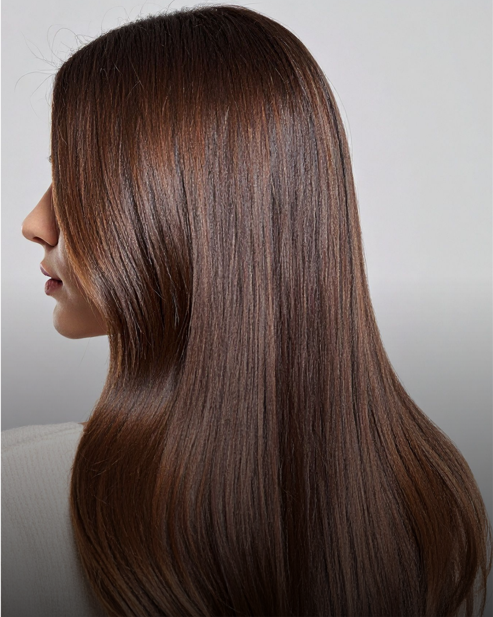 Person with long, straight, blowout hair facing away from the camera, showing the hair’s shine and texture.