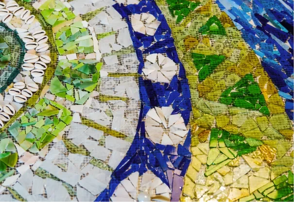 Close-up of a colorful mosaic with various shades of green, blue, white, and yellow tiles arranged in patterns.