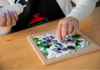 Person playing a mosaic board game with colorful tiles on a wooden surface.