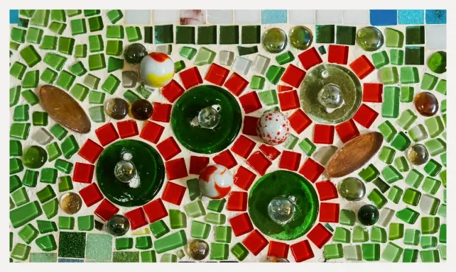 Decorative mosaic featuring three green glass candle holders surrounded by red, green, white, and brown glass tiles and small decorative balls.