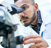 Scientist examining a sample through a microscope.