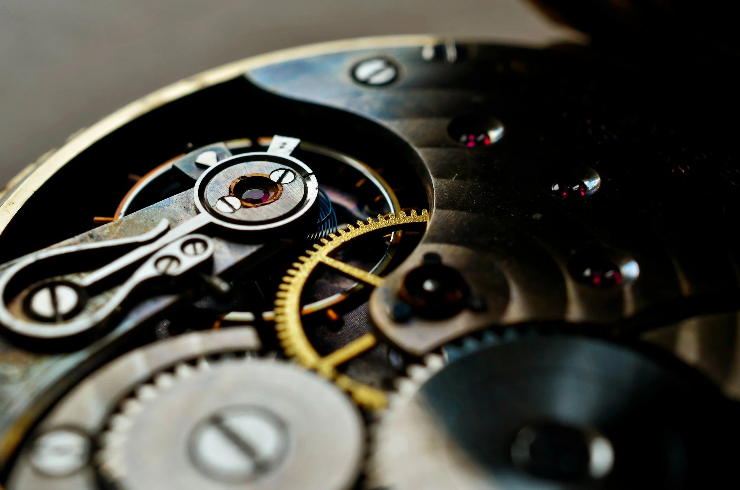 Close-up of the intricate inner mechanism of a mechanical watch with gears, screws, and metal components.