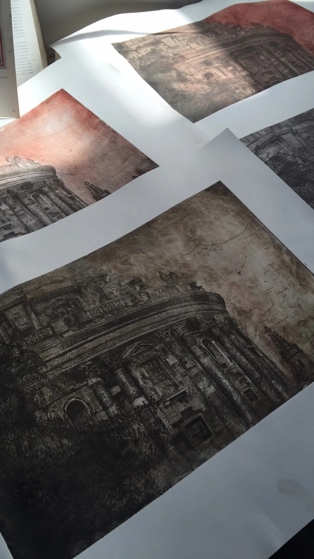 Printouts of archival photographs of a historic building with elaborate architectural details, laid out on a table.