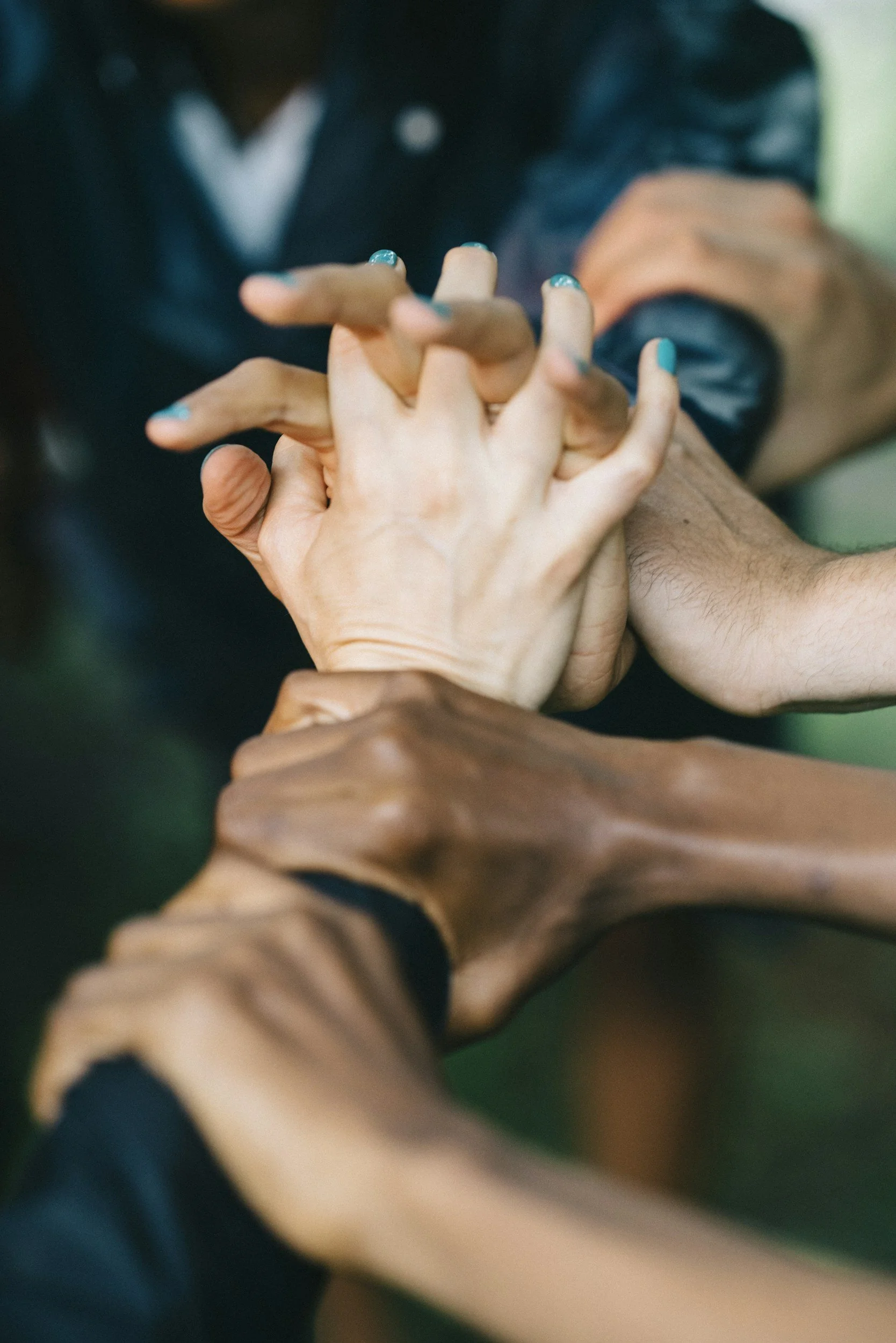 Multiple hands of different skin tones intertwined, symbolizing unity and teamwork, aligned with Journey Confluence mission vision and values.