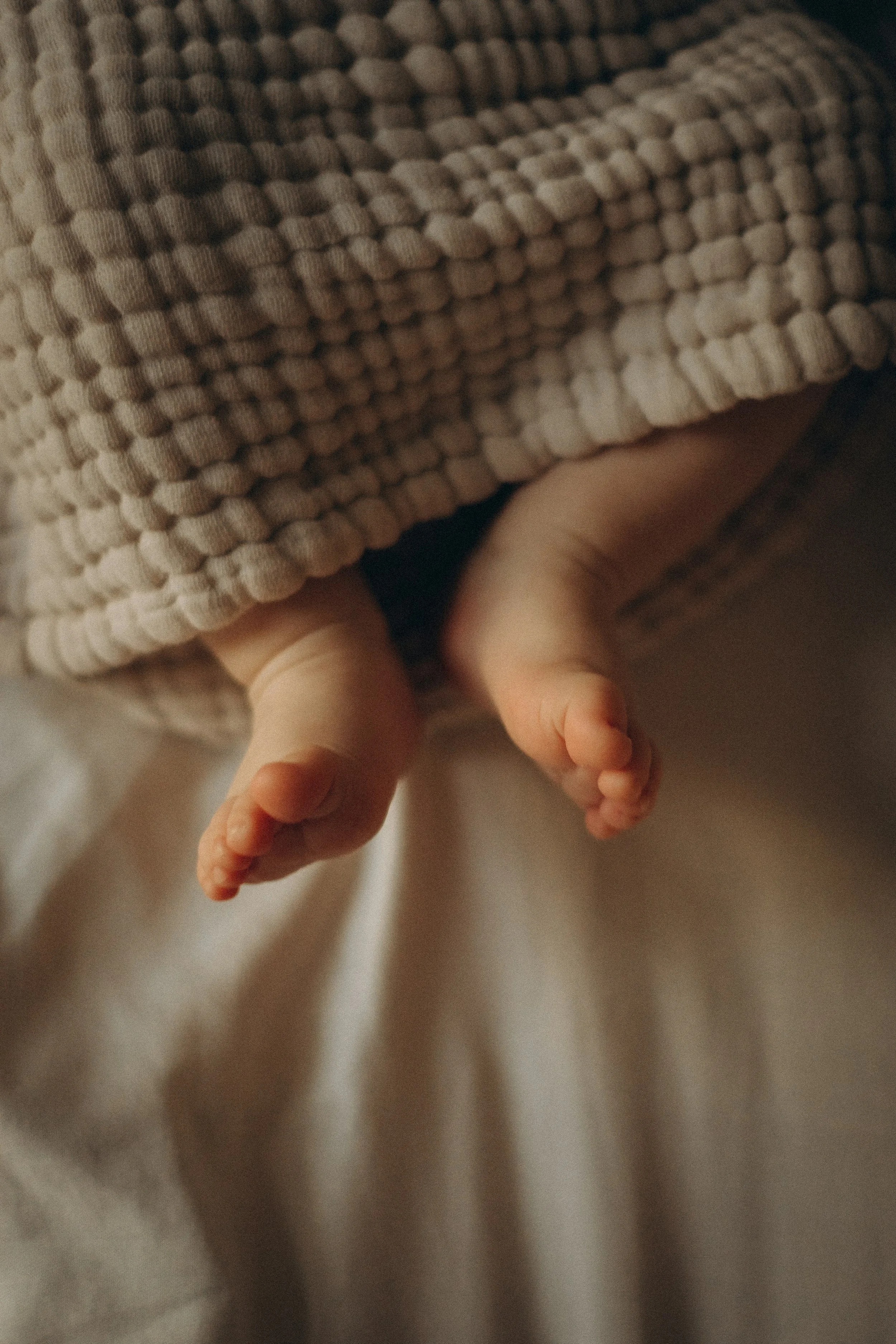 Photo of baby feet peeking out of blanket.