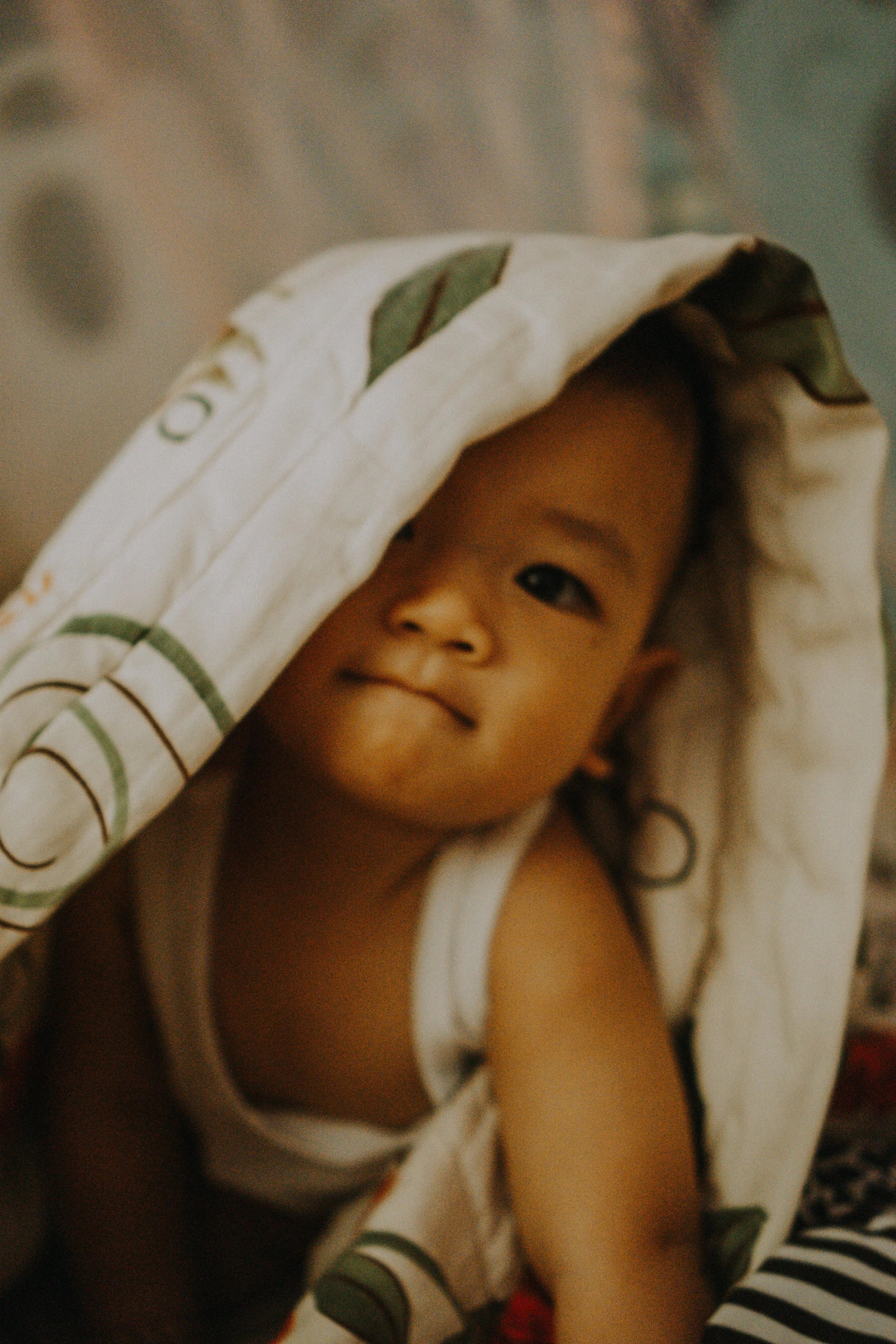 Photo of toddler, awake, peeking out of blanket.
