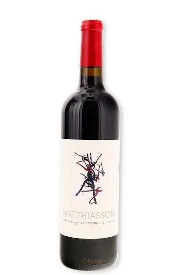 A bottle of red wine with a red foil capsule and a white label featuring a black and red illustration of an ant.