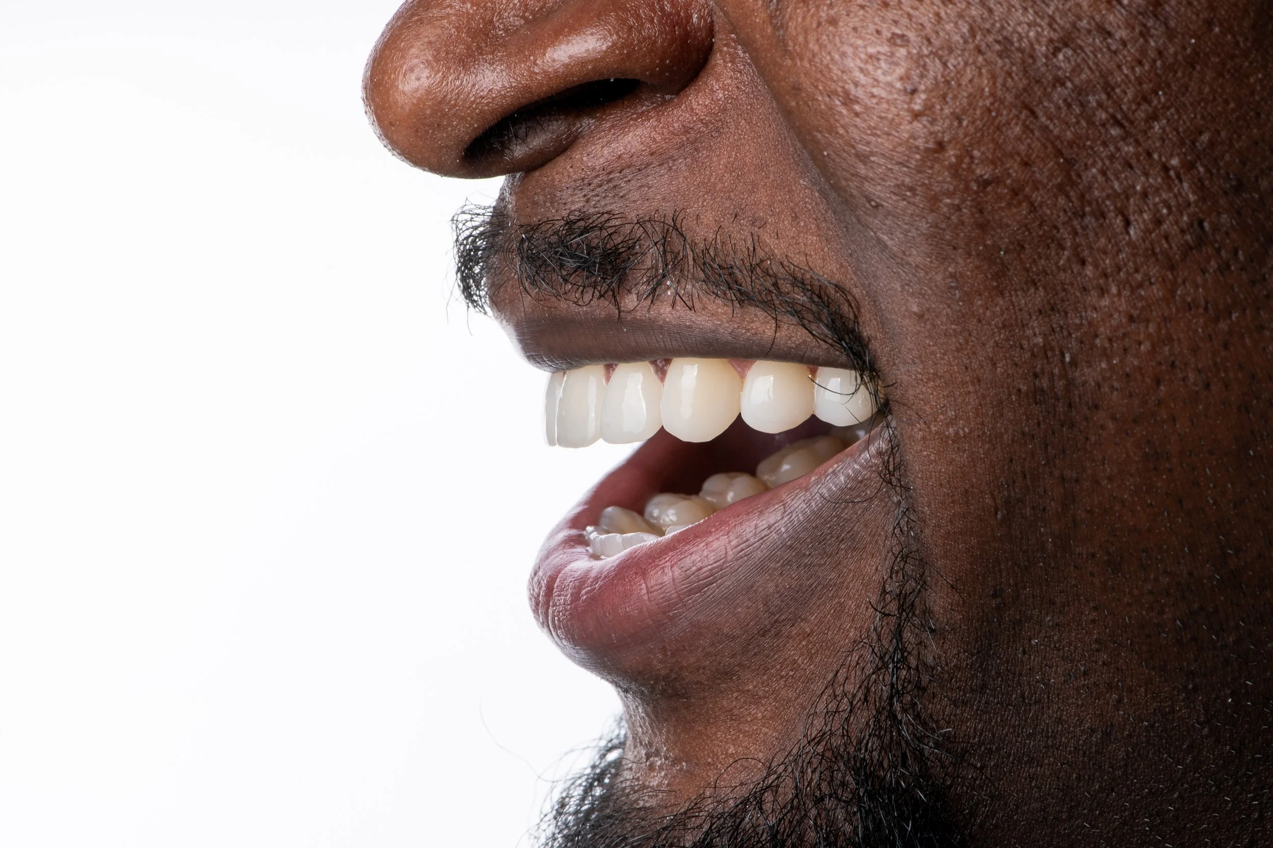 Close-up of a person's face showing their nose, mouth, and beard, with a wide smile revealing white teeth.