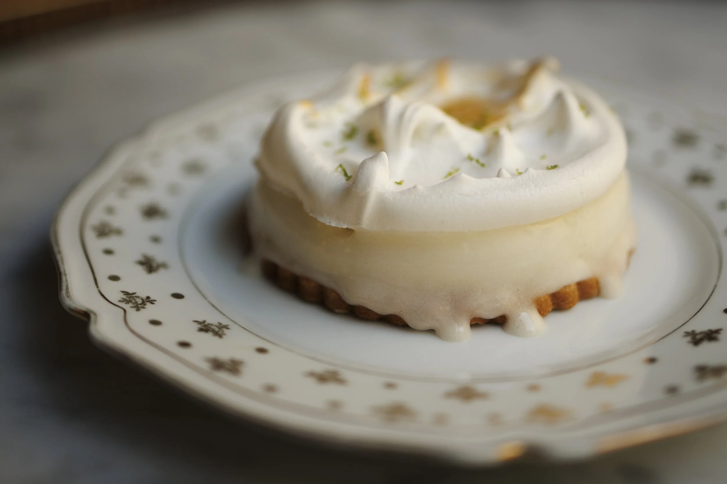 Glace au citron sur un sablé et recouvert d'une meringue française. La glace est à déguster sur une assiette en porcelaine à la pâtisserie Chez Apolline