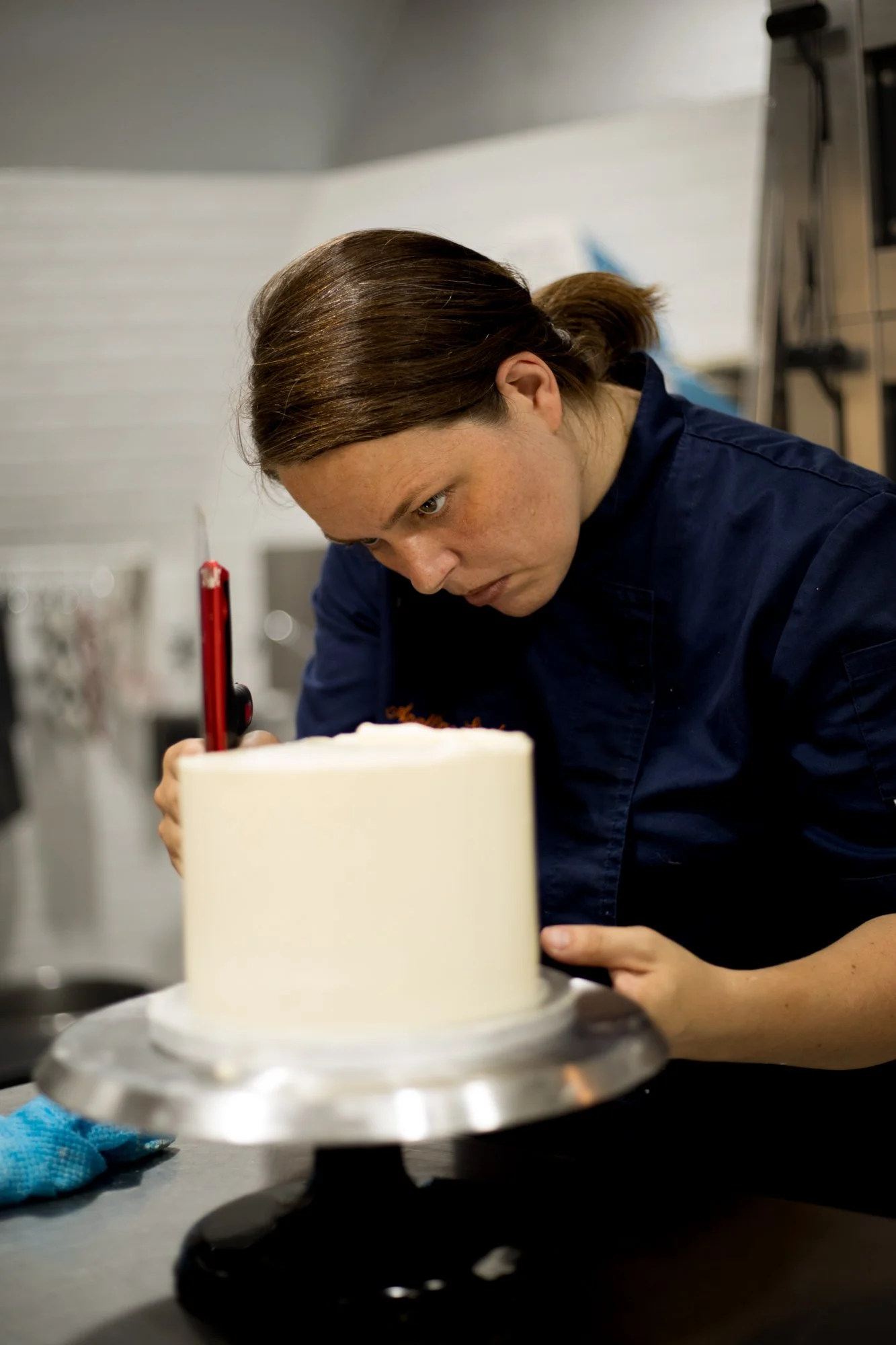 Apolline Luis Siméon, cheffe pâtissière lisse un gâteau de mariage.