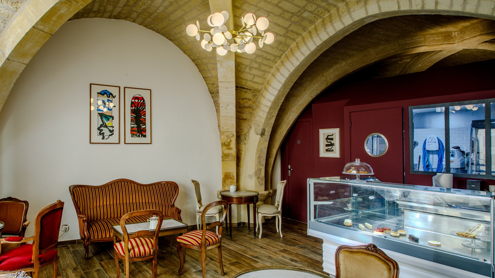 Salon de thé cosy à Montpellier dans une salle voutée et décoration alliant meuble d'époque et art contemporain.