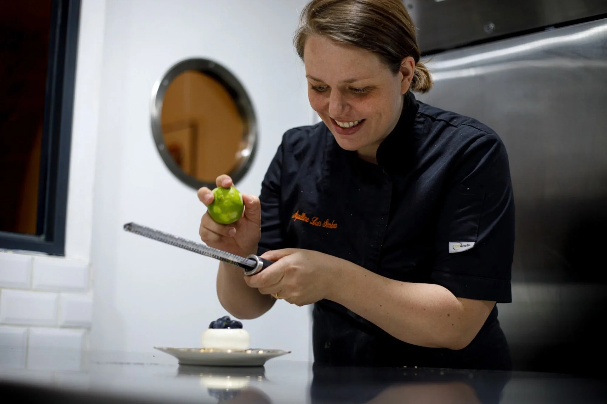 La cheffe pâtissière Apolline Luis Siméon sourire aux lèvres lors de la sublimation d'un entremet à la myrtille