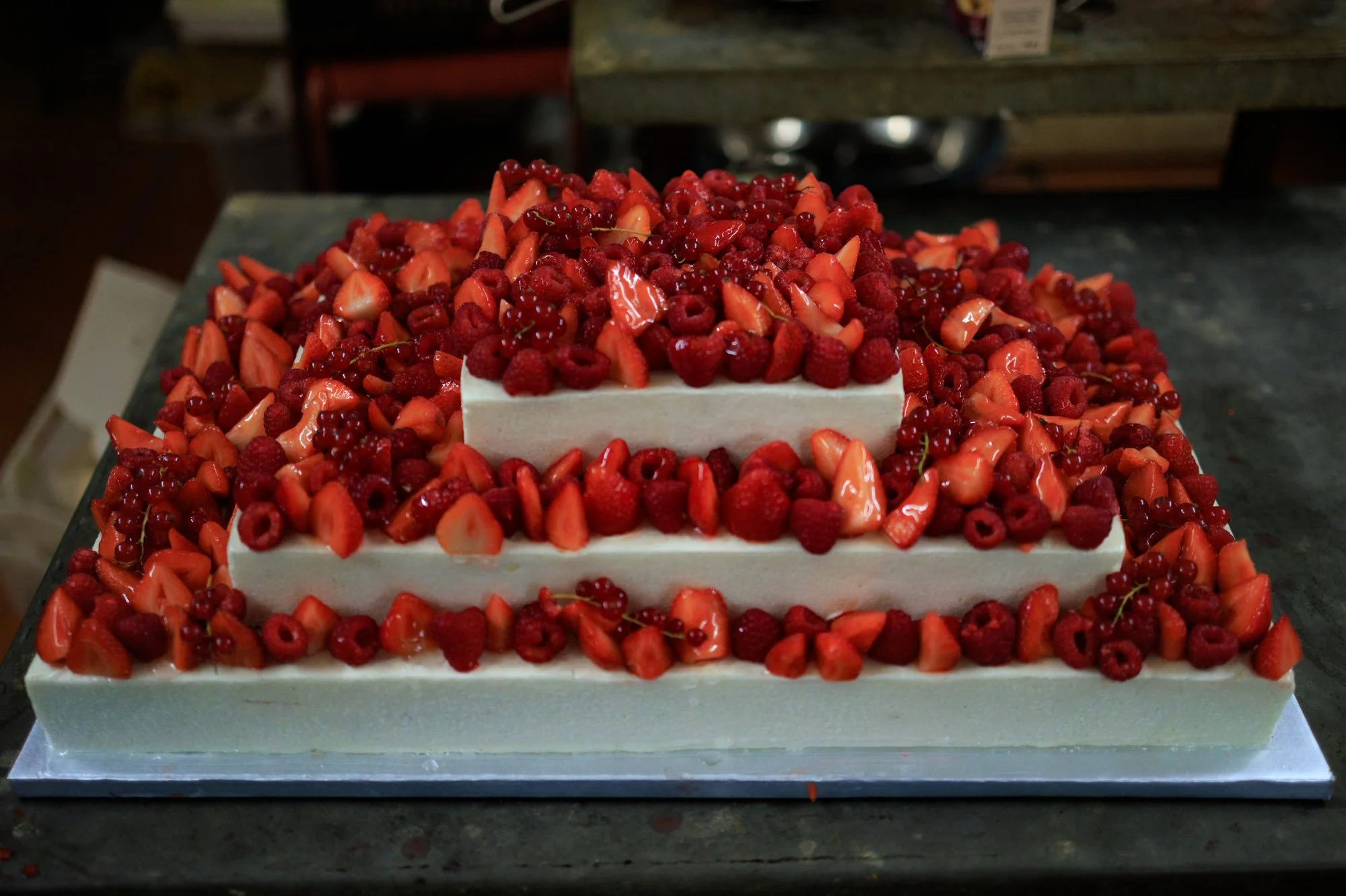 Gâteau monté de mariage rectangulaire sur 3 étages. Mousse vanille décoré de fruits rouges, fraises, framboises et groseilles.