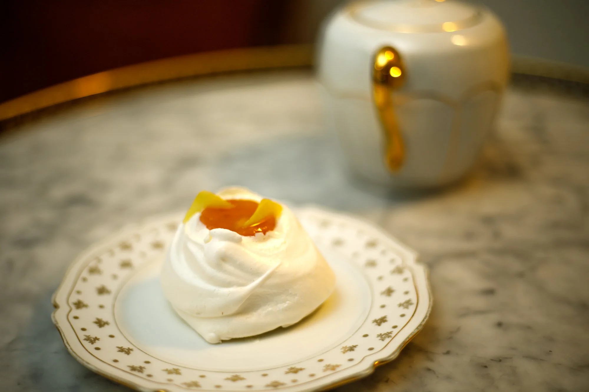 Pavlova à la pêche et au gingembre servie sur une assiette en porcelaine.