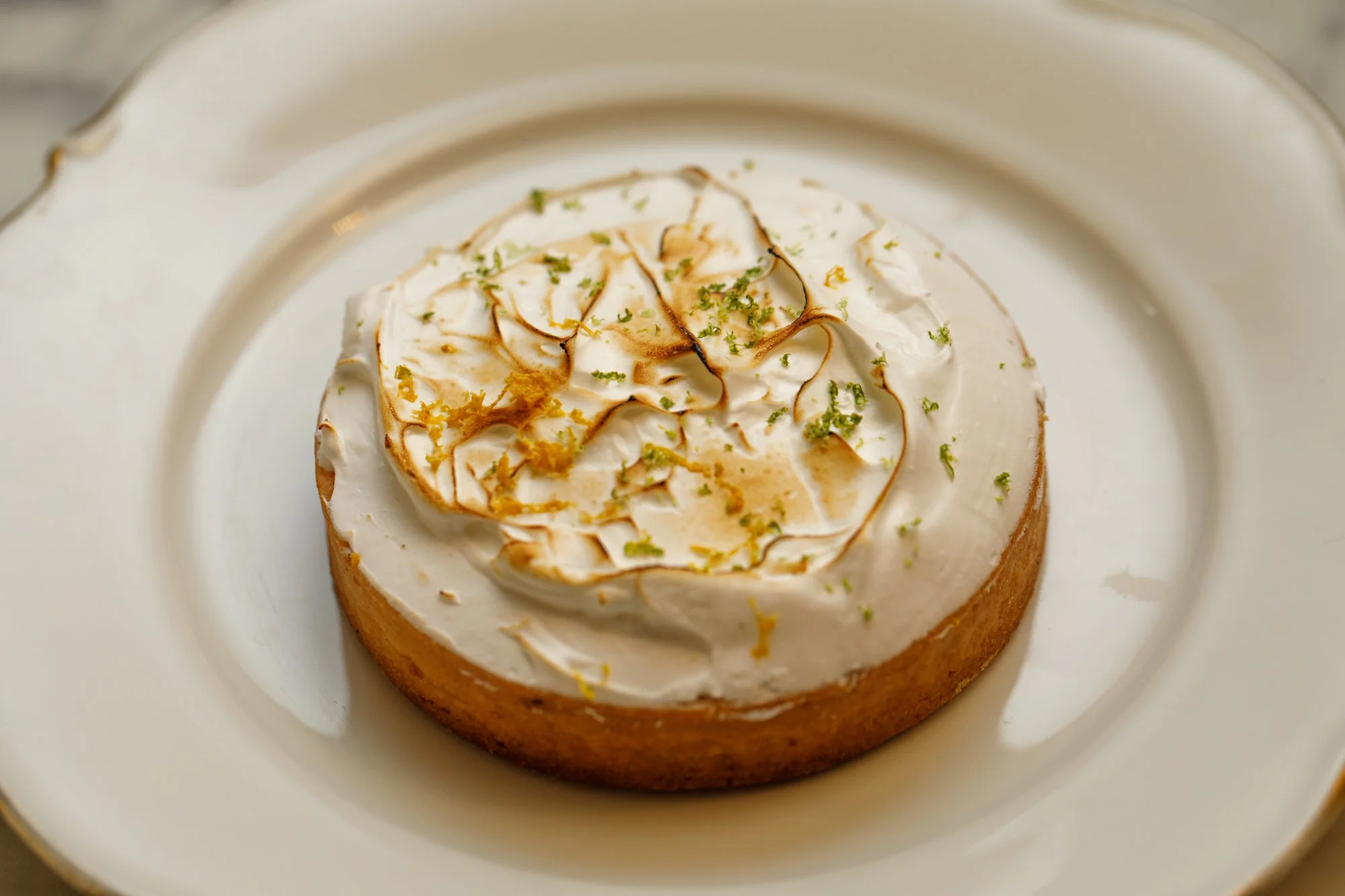 Tarte au citron meringuée artisanale avec zestes de citron vert, servie dans une assiette ancienne de la pâtisserie Chez Apolline à Montpellier