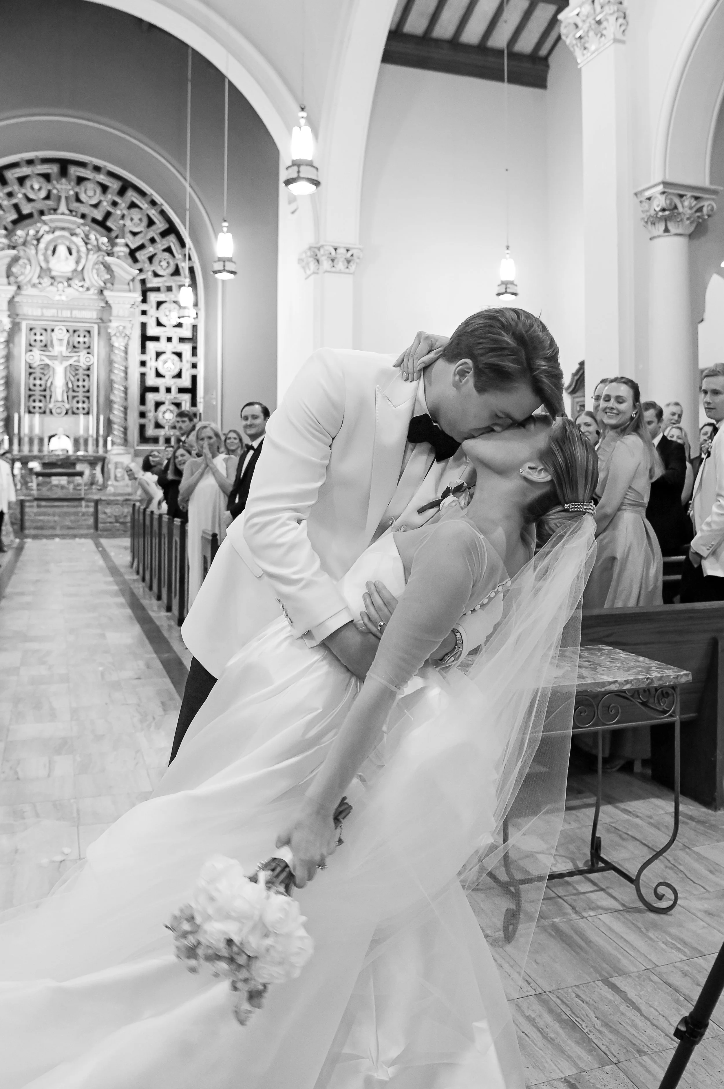 A bride and groom sharing a kiss during their wedding ceremony in a church with guests in attendance.
