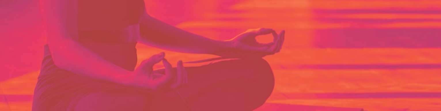 Person practicing meditation or yoga in a seated position during sunset or sunrise inside a building or porch.