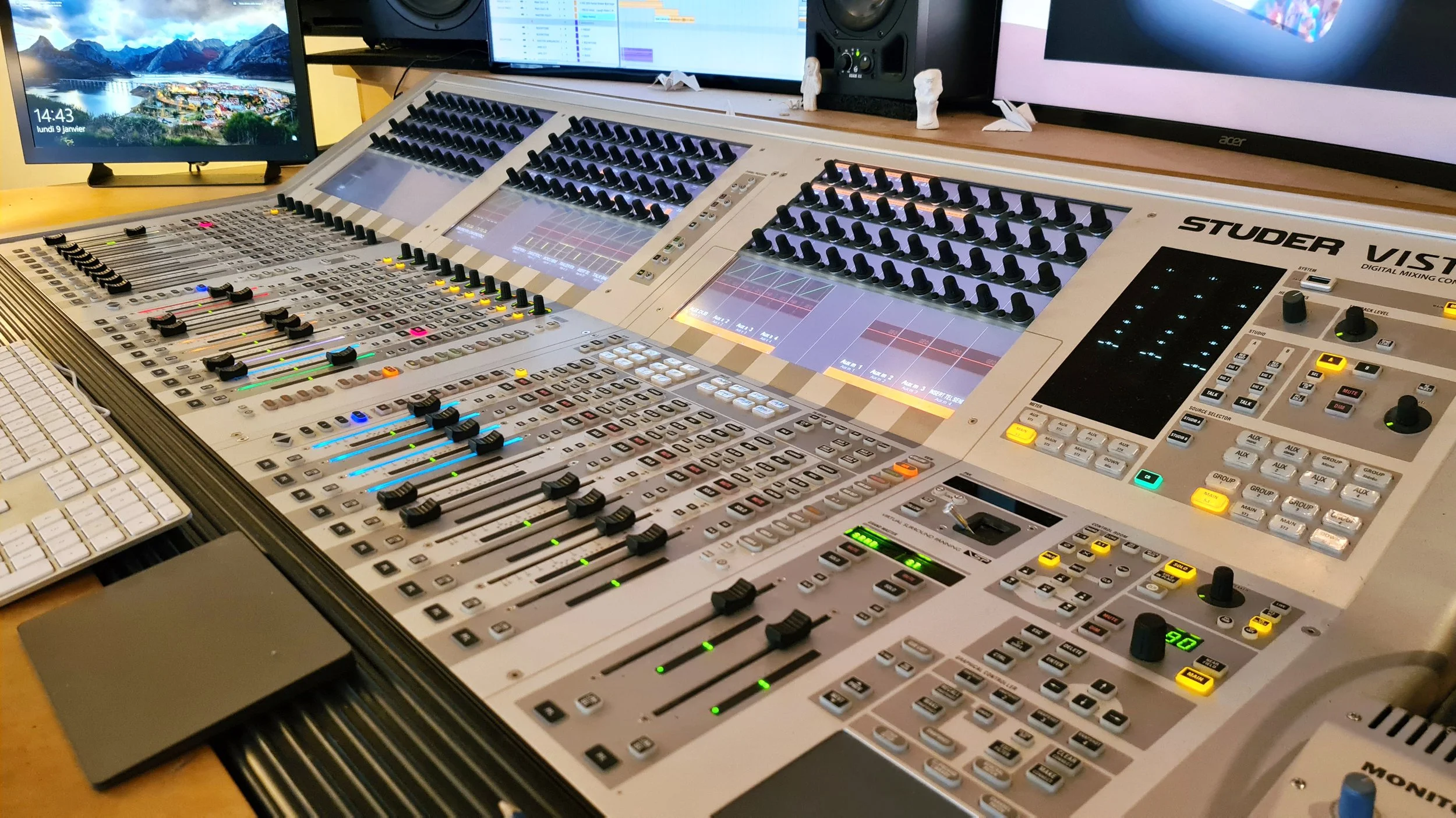 Une console de mixage audio avec plusieurs boutons, faders et écrans numériques, utilisée pour la production musicale ou le son en studio.