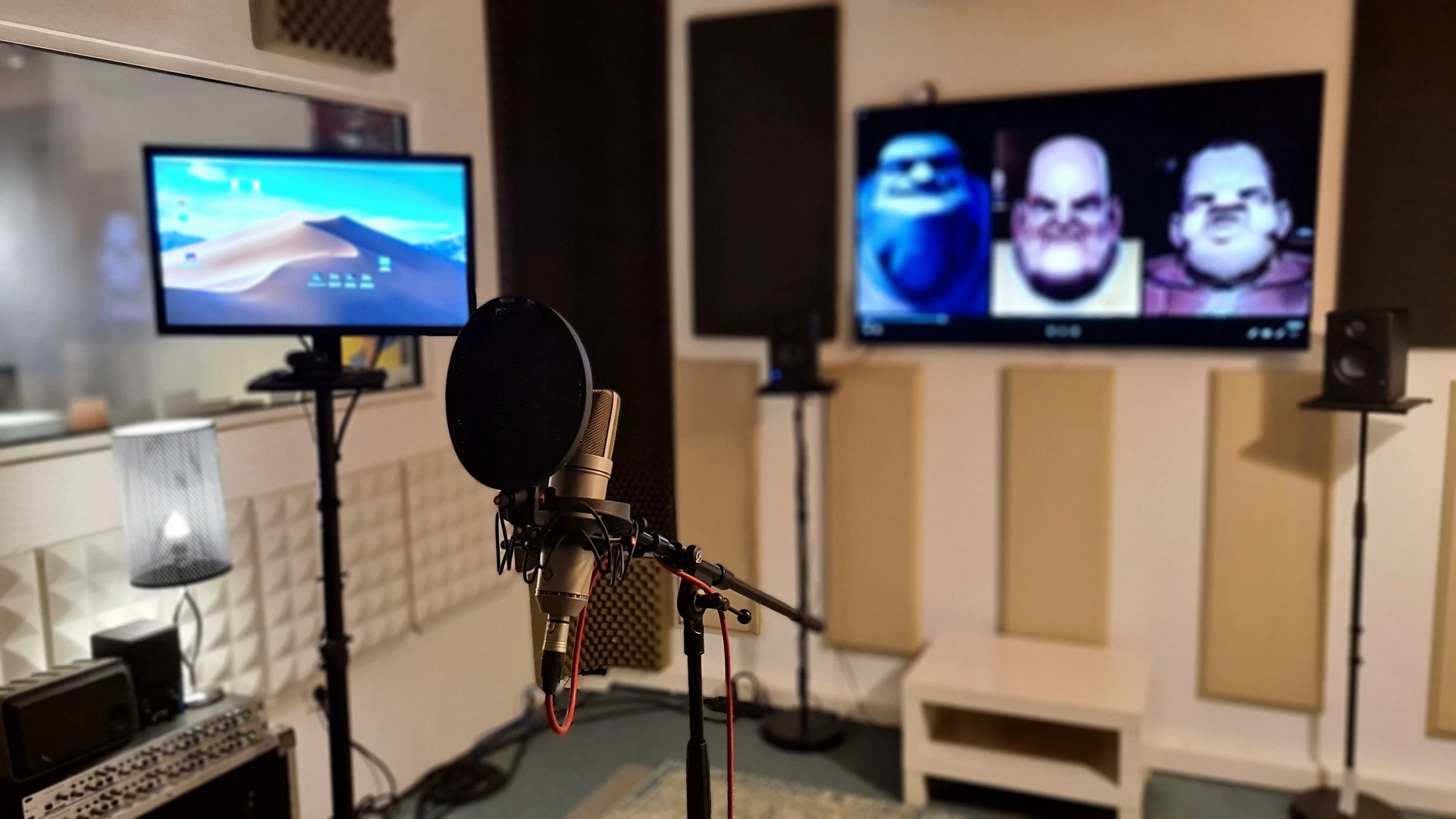 Une salle d'enregistrement ou de création de contenu avec un microphone professionnel, une paire de moniteurs de studio, un écran affichant des personnages de dessin animé, et un autre écran d'ordinateur. Il y a aussi du matériel audio sur une étagèr