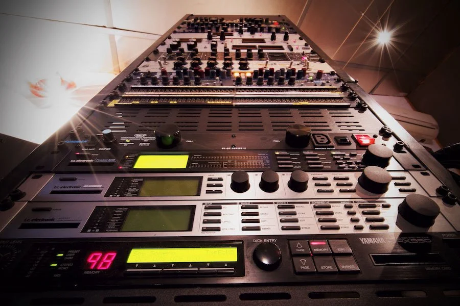 Table de mixage audio professionnelle avec nombreux boutons, curseurs et écrans LCD, utilisée pour le son enregistrement ou en concert.