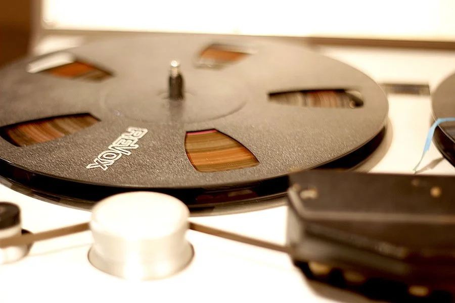 Une bobine de film cinématographique vintage noire et une machine à projeter ou à enrouler de film, en gros plan.