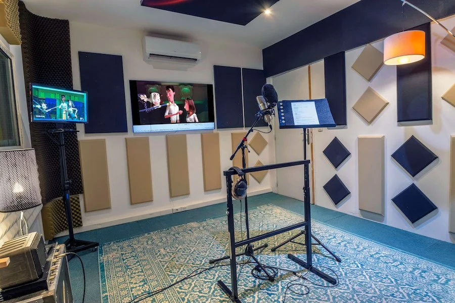 Salle d'enregistrement sonore avec microphones, écran de lecture, et dispositifs d'isolation phonique