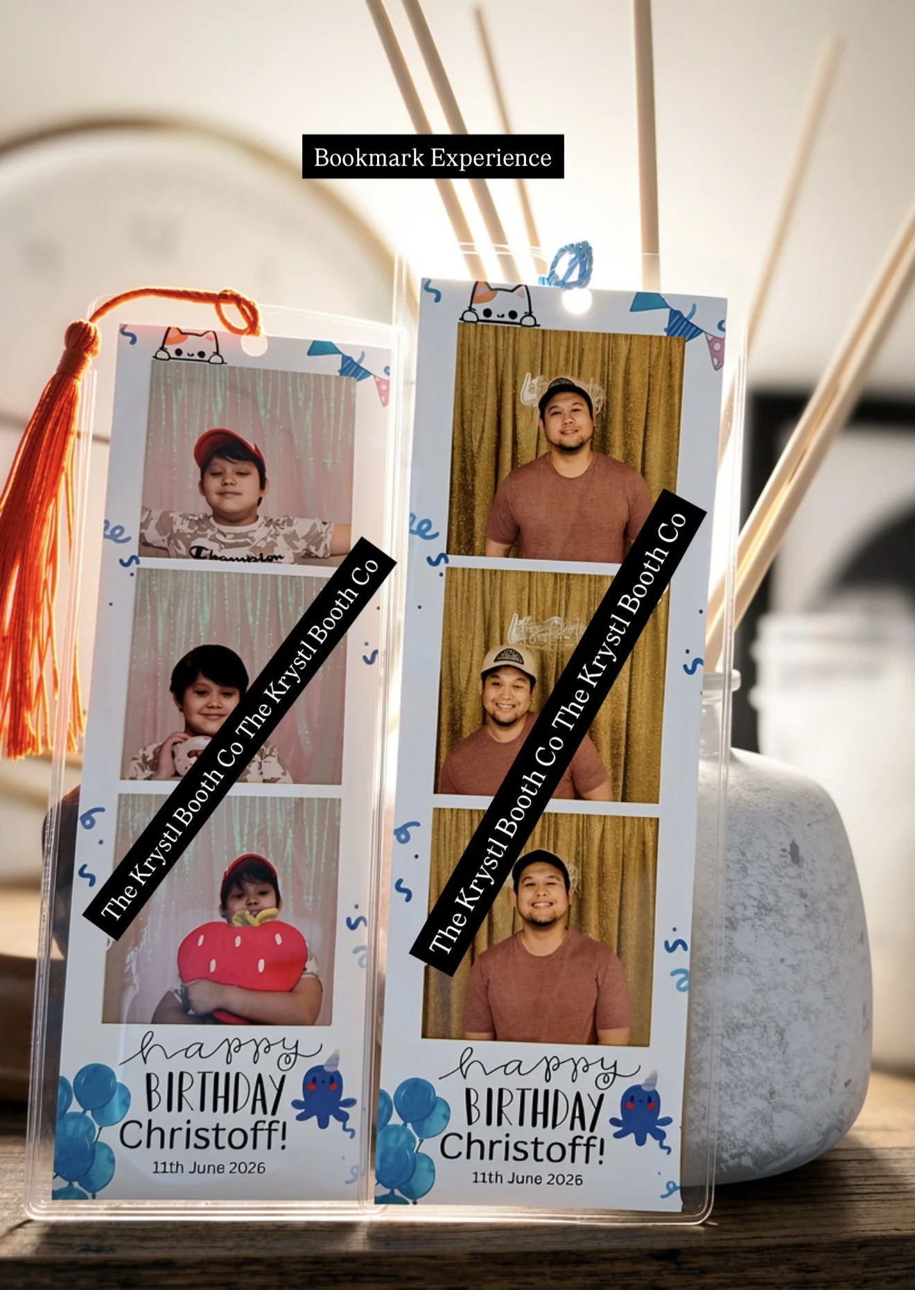 Photo of two birthday party photo booth strips, each with four pictures of a man and a child, decorated with blue balloons and a crab illustration. The first strip shows the child wearing a red hat and holding a yellow toy; the second strip shows the man in a brown shirt and baseball cap. Both strips include the text 'Happy Birthday Christoff! 11th June 2026' and the phrase 'The Krystl Booth Co' as a watermark.