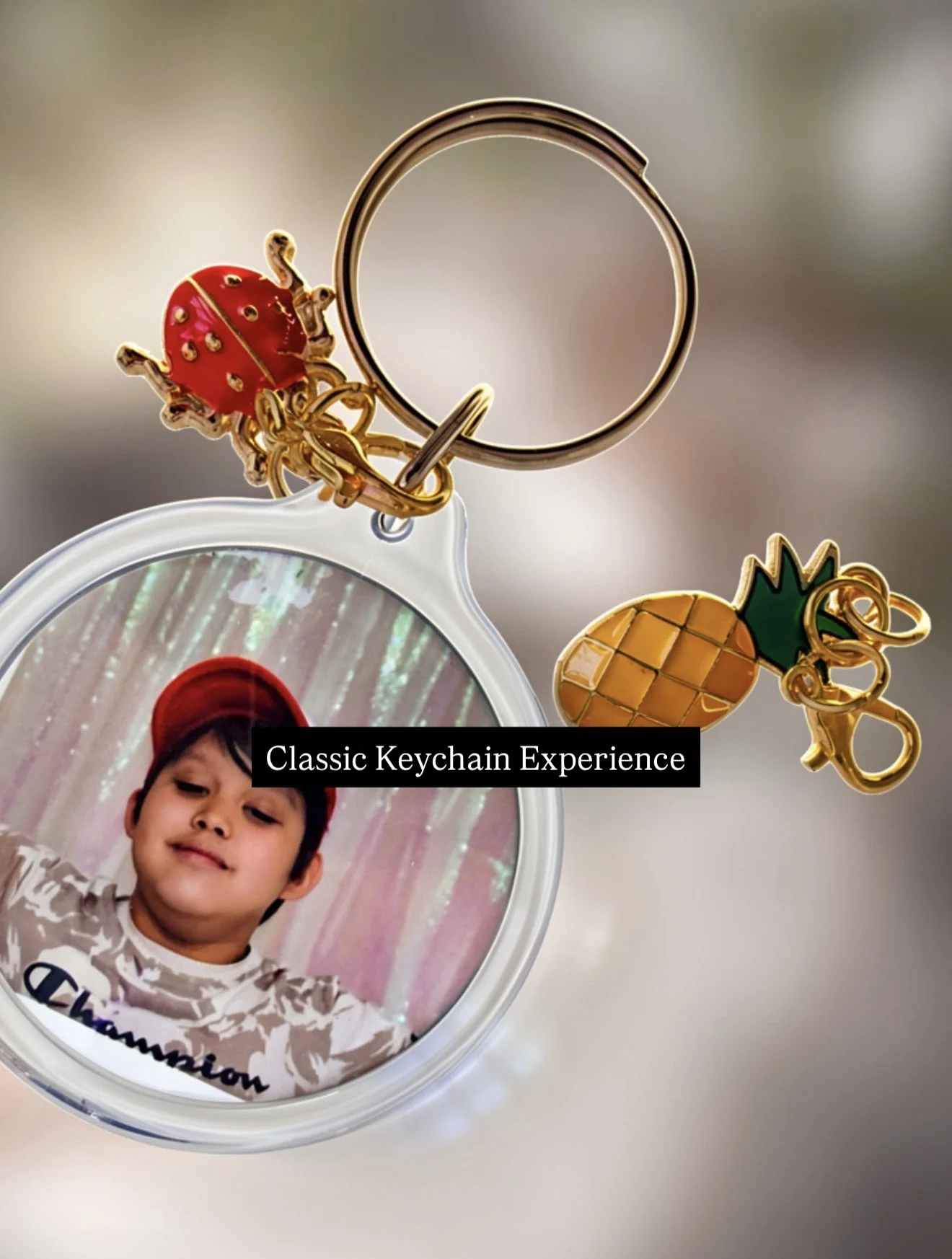 A photo of a keychain with a red ladybug and a pineapple charm, attached to a circular mirror frame holding a photo of a young boy wearing a red cap. Text overlay says 'Classic Keychain Experience'.
