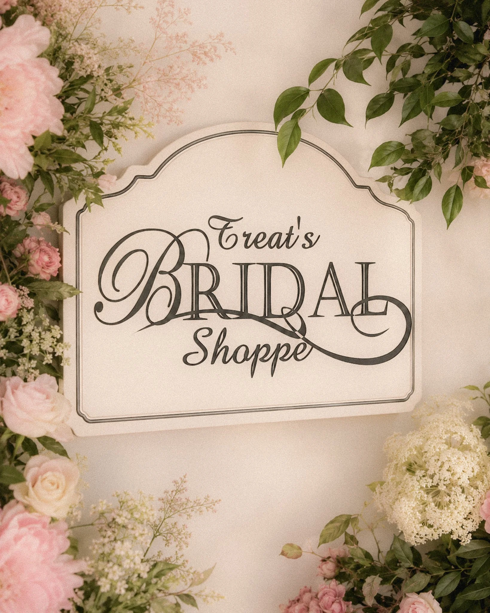 Decorative wedding sign reading "Treat's Bridal Shower" surrounded by pink and white flowers and green foliage.