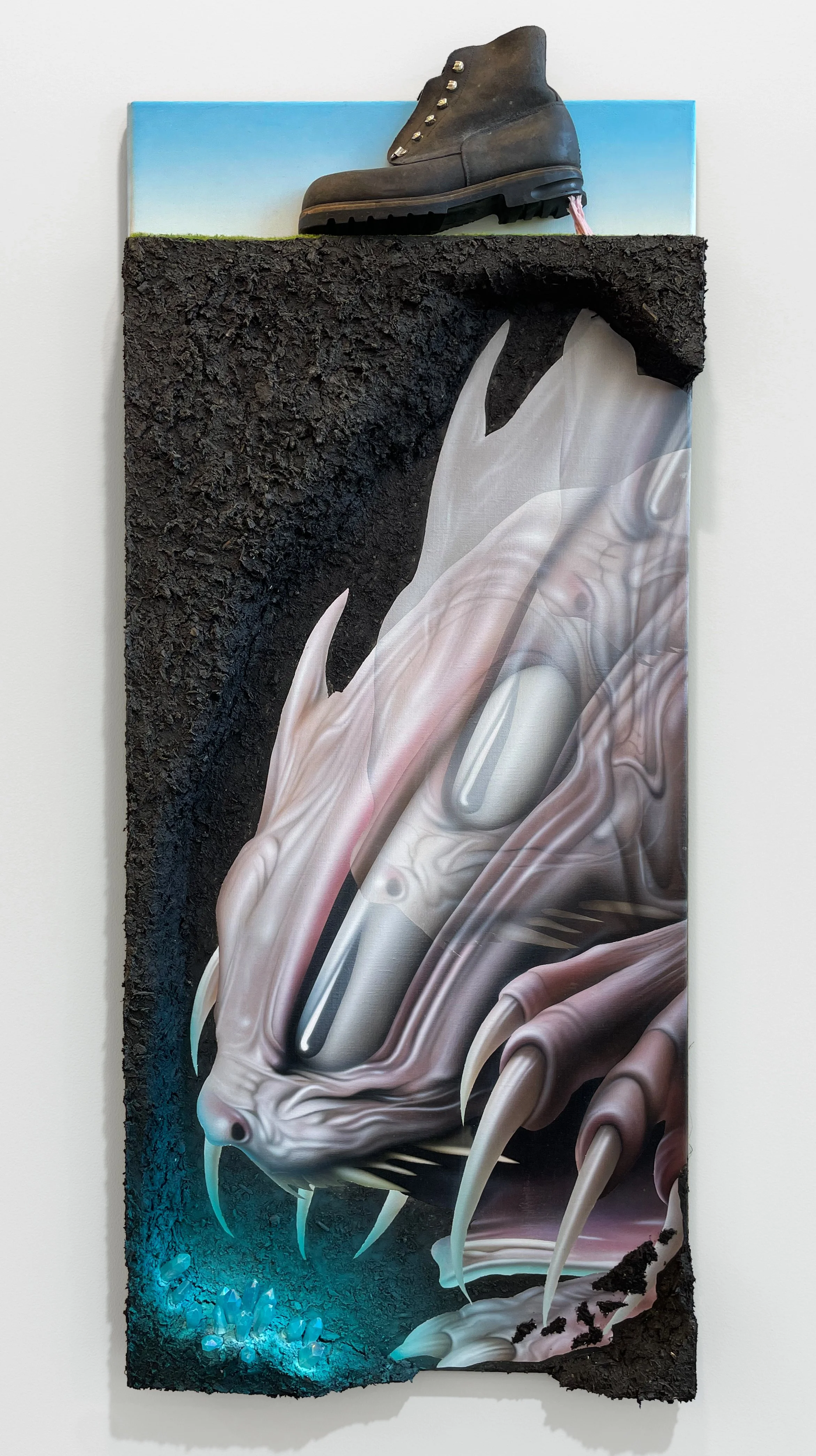 “From A Gentle Nurturing Energy To Open The Throat Chakra”, 2024, acrylic, expandable foam, mud, polystyrene foam board, static grass strips, leather shoe, chewing gum, epoxy, and gemstones on linen canvas, 127 x 56.5 x 11 cm, 50 x 22.2 x 4.3 in