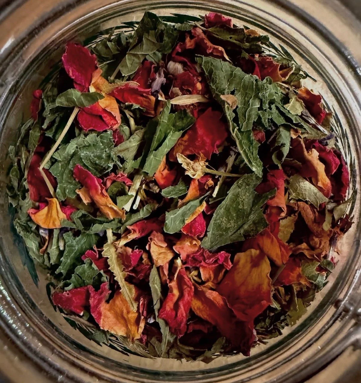 A jar filled with dried, colorful flower petals and leaves.