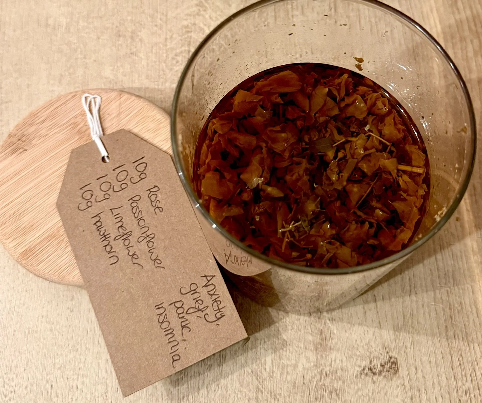 A glass of dried hibiscus flowers steeping in water with a handwritten tag next to it.