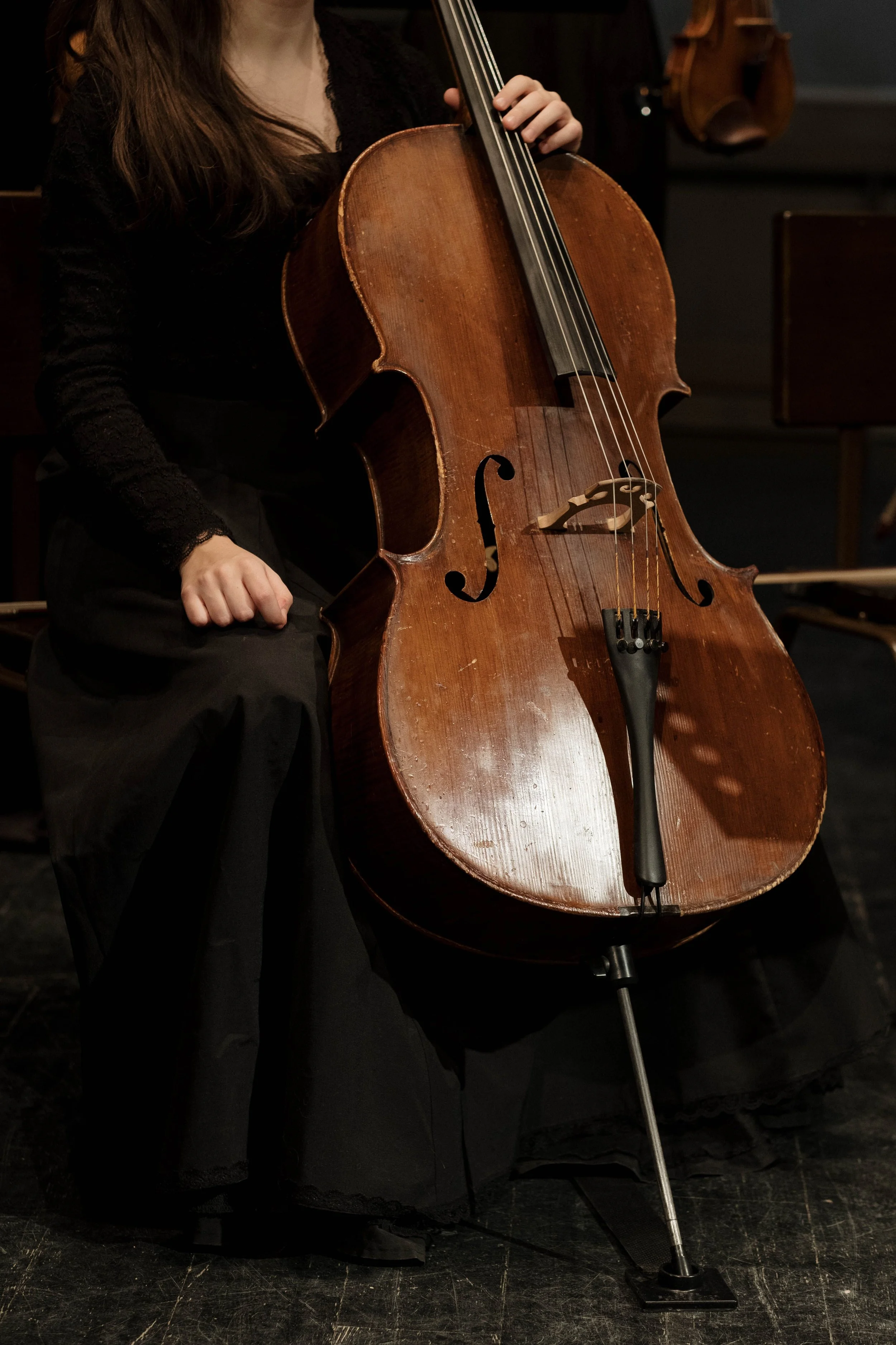 A woman in black clothing playing a cello on stage.