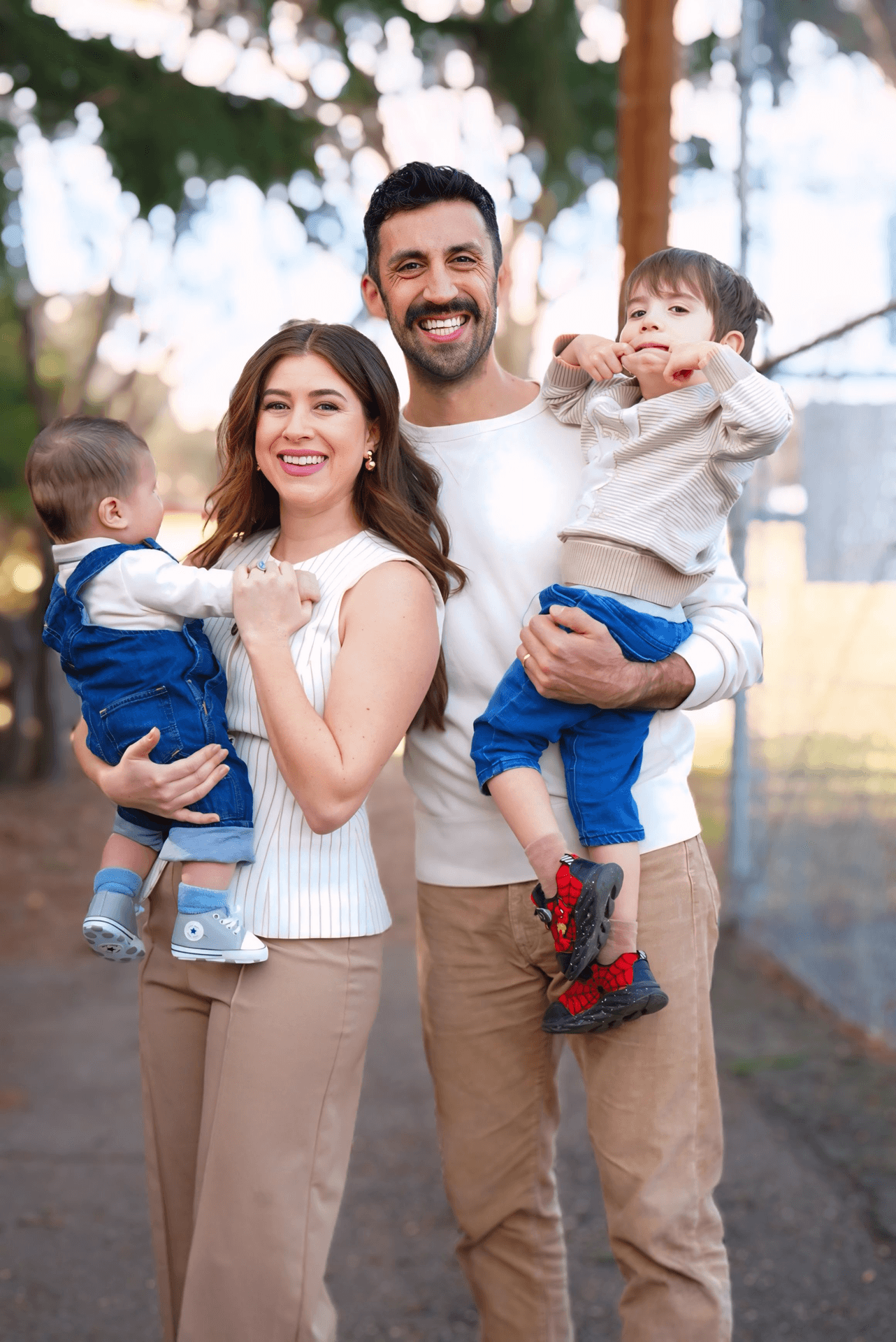 A happy family of four enjoying outdoor time, with a woman, man, and two young boys smiling and posing for the camera.