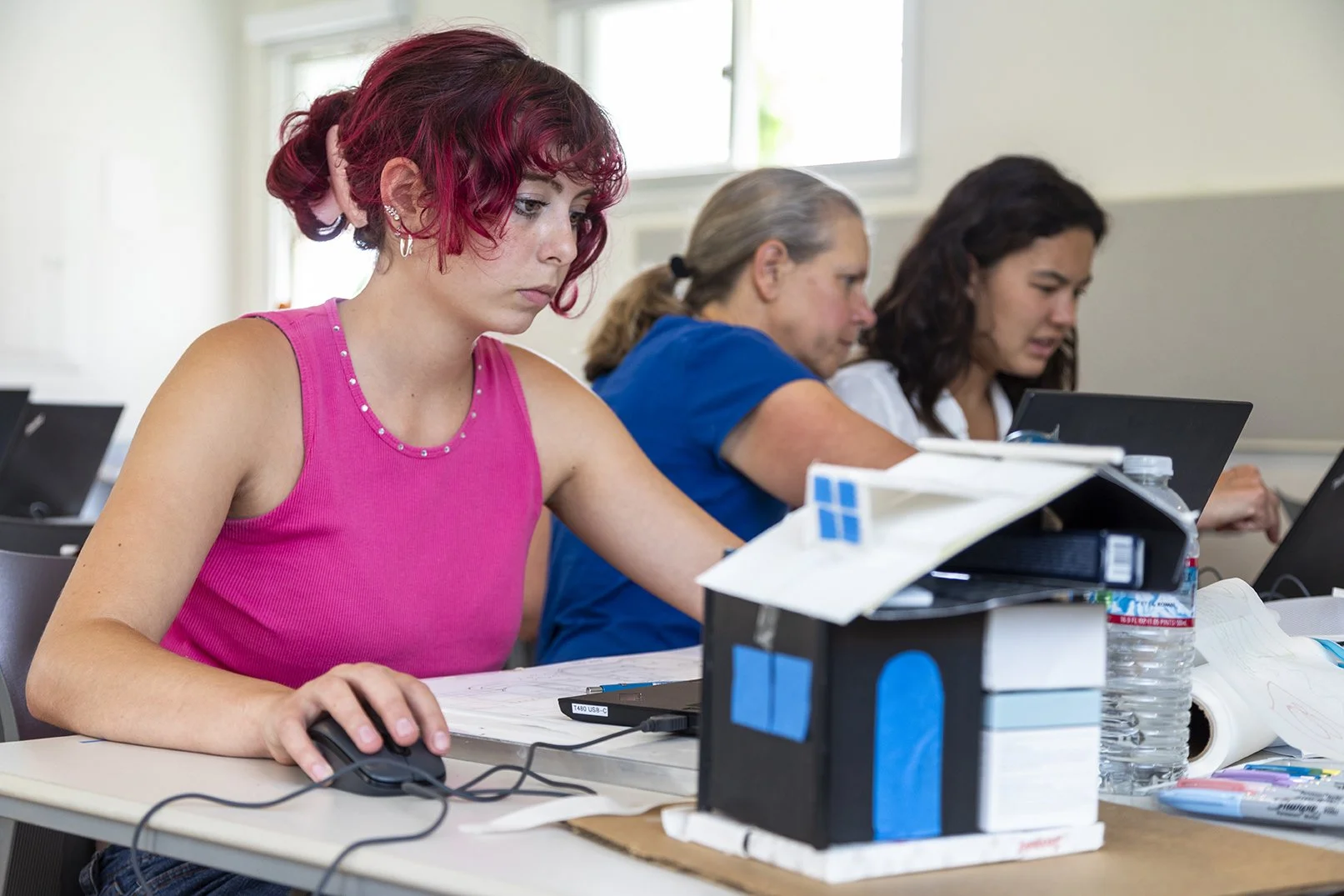 students working on CAD software with teachers in architecture camp. A model house can be seen