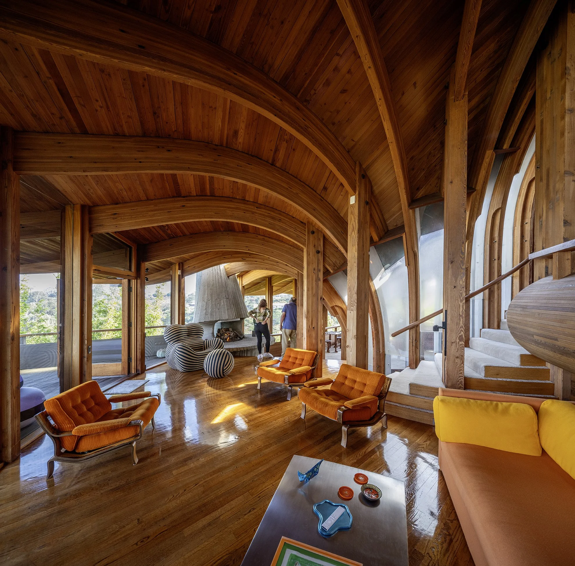 interior image of mid-century modern home with curved wood ceilings surrounded by walls of windows