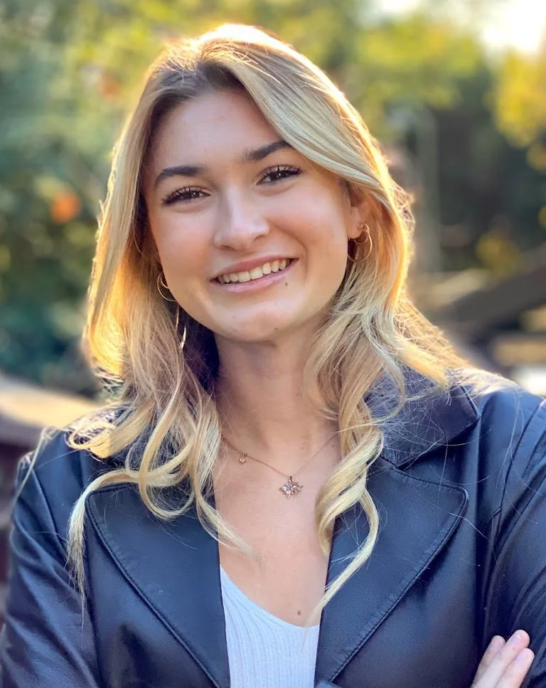 blonde woman smiling in a jacket outside
