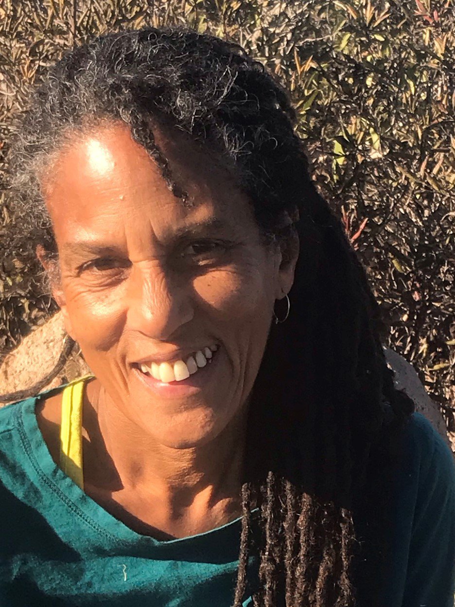 woman smiles with a side ponytail in nature