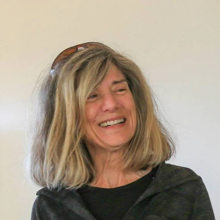 laughing woman with shoulder length hair and sunglasses on her head